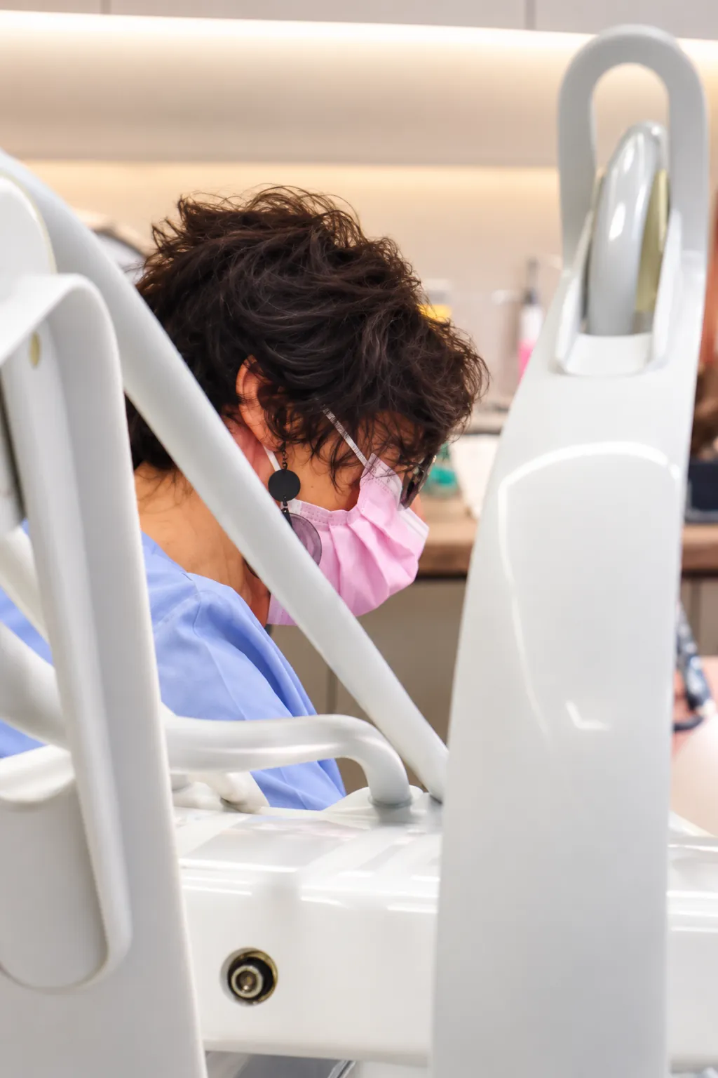 Odontóloga con mascarilla trabajando junto a la unidad dental
